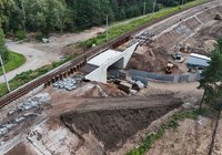 Z perspektywy lotu ptaka widok na nowo budowany wiadukt kolejowy w Suchedniowie. Widoczne są betonowa konstrukcja obiektu, teren robót ziemnych, zaplecze budowy oraz linia kolejowa przebiegająca nad inwestycją.